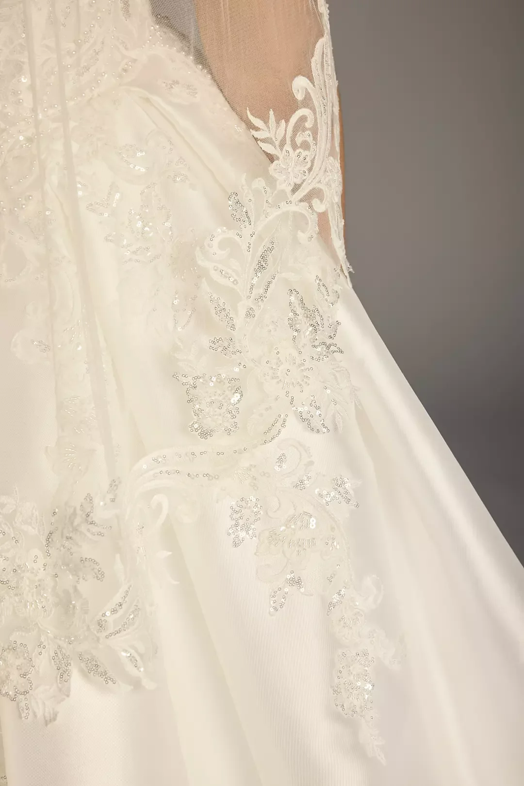 Close-up of a white wedding dress with lace and sequin embroidery.