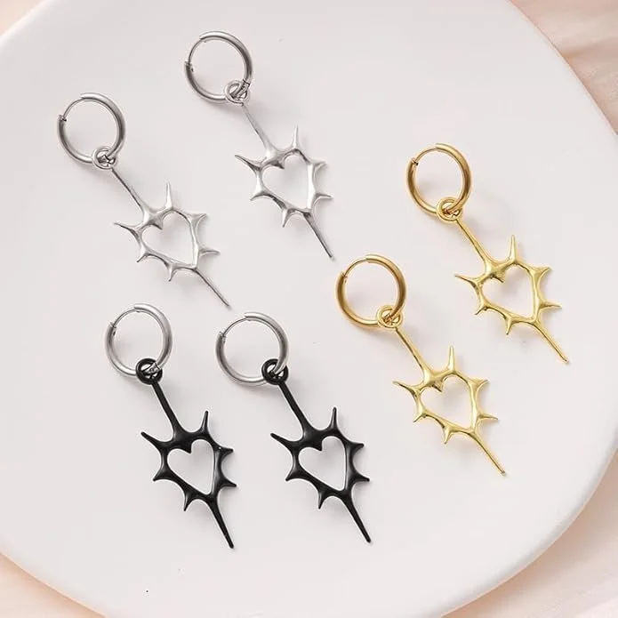 Three pairs of star-shaped dangle earrings in silver, black, and gold colors displayed on a white surface.