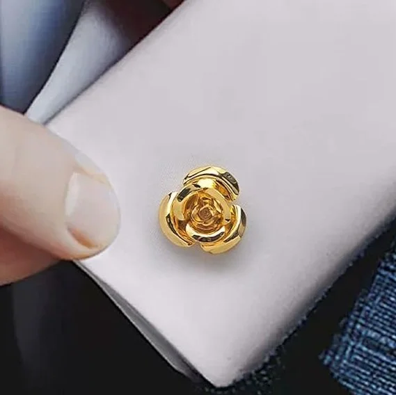 Close-up of a gold flower-shaped ring on a white jewelry display pad, with a person's finger nearby.