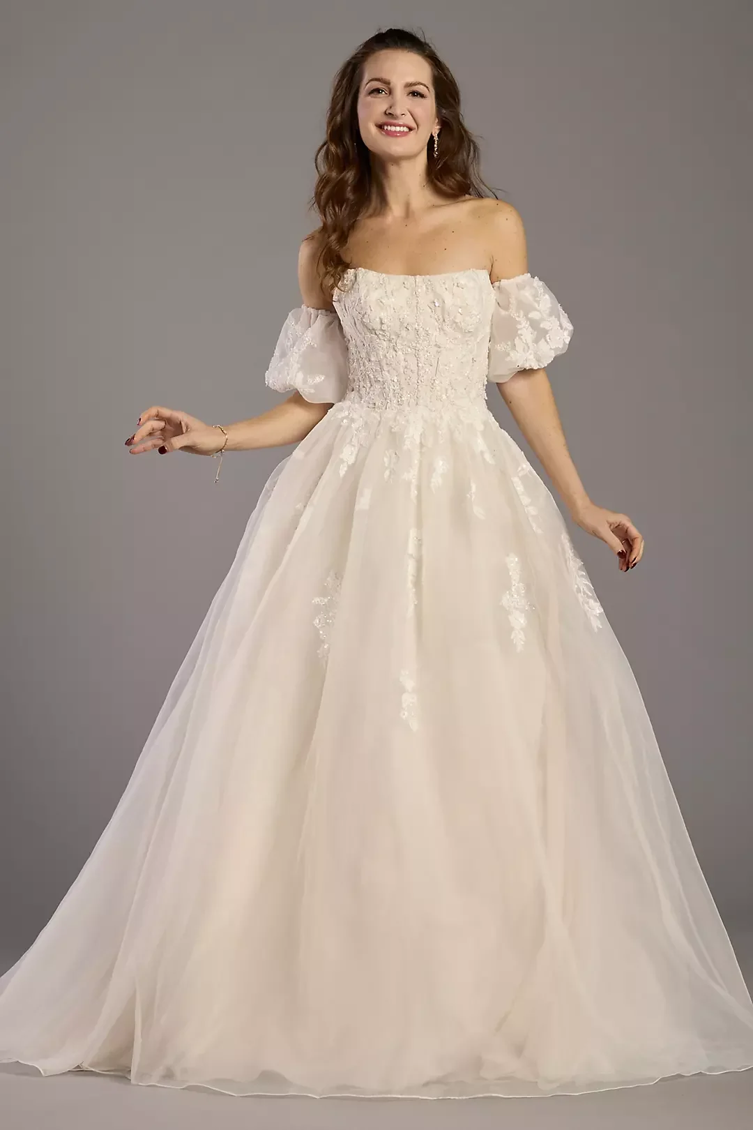 Woman smiling in a wedding dress with puffed sleeves and lace details.
