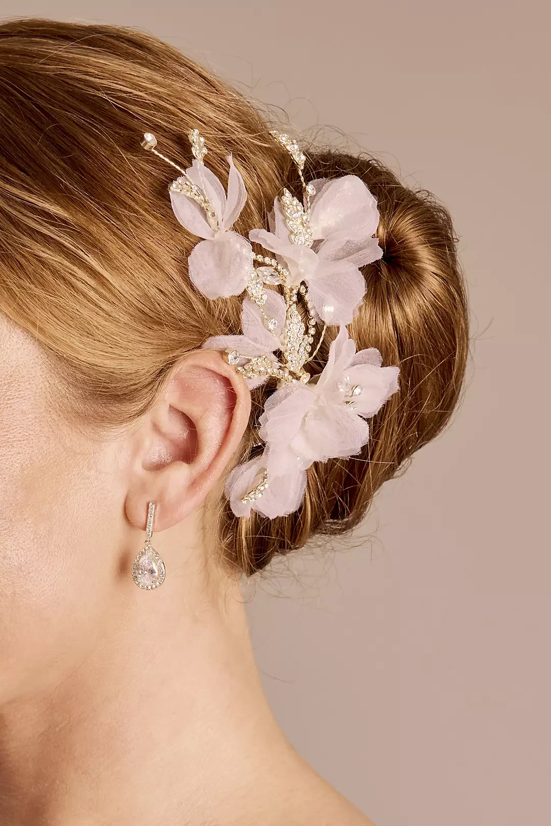 Close-up of a woman's ear with a pearl earring, and an elaborate silver and pearl hair accessory with pink fabric flowers.