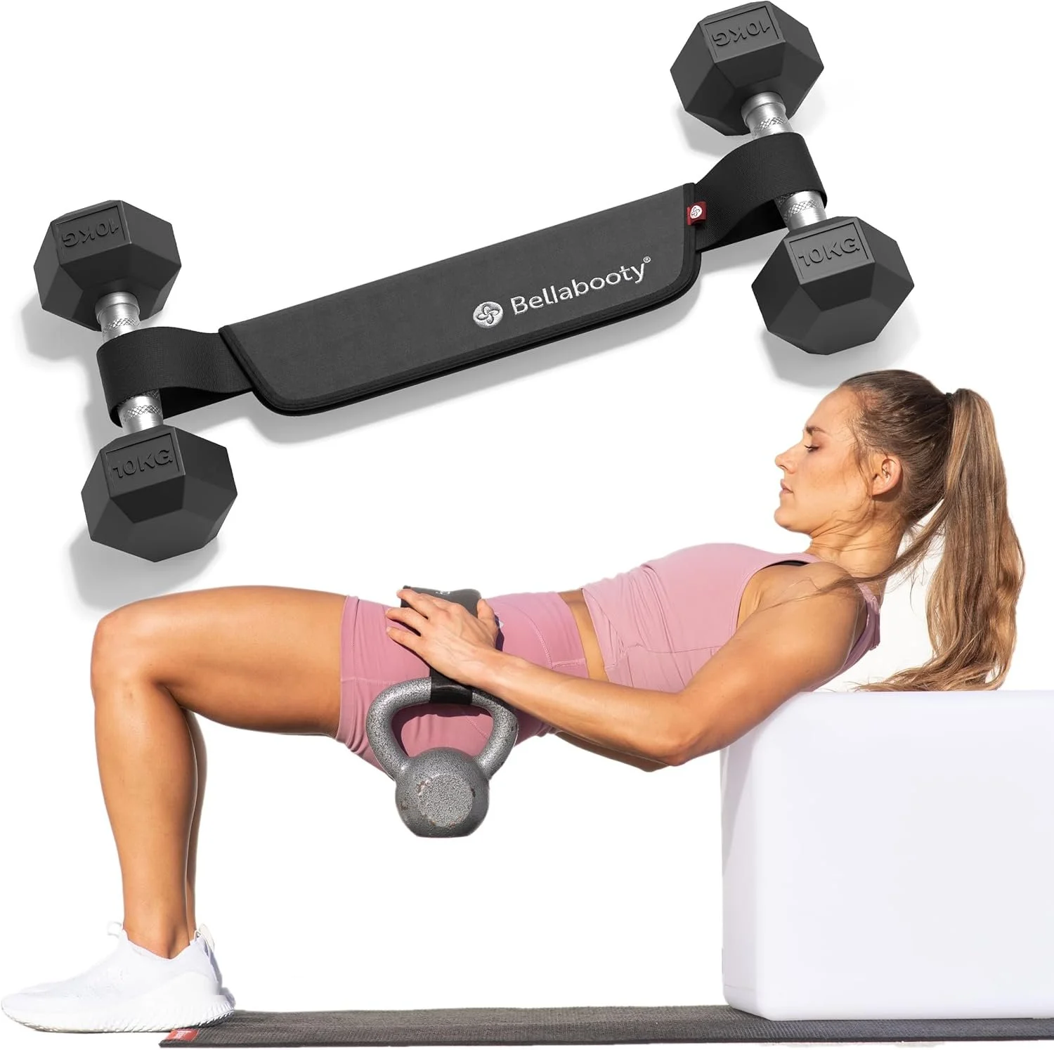 A woman lying on a bench doing a glute bridge exercise with a kettlebell on her hips, a black resistance band around her thighs, and a wall-mounted resistance band anchor with dumbbells attached above her in a fitness studio.