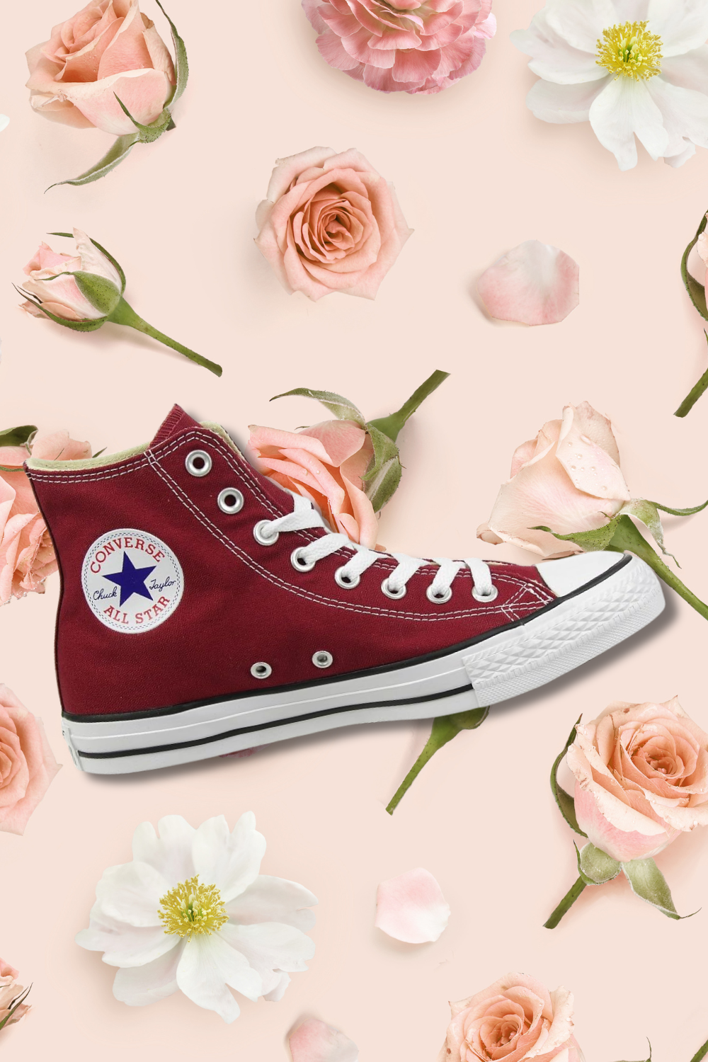A red Converse Chuck Taylor All Star sneaker placed on a light pink background with scattered roses and rose petals.