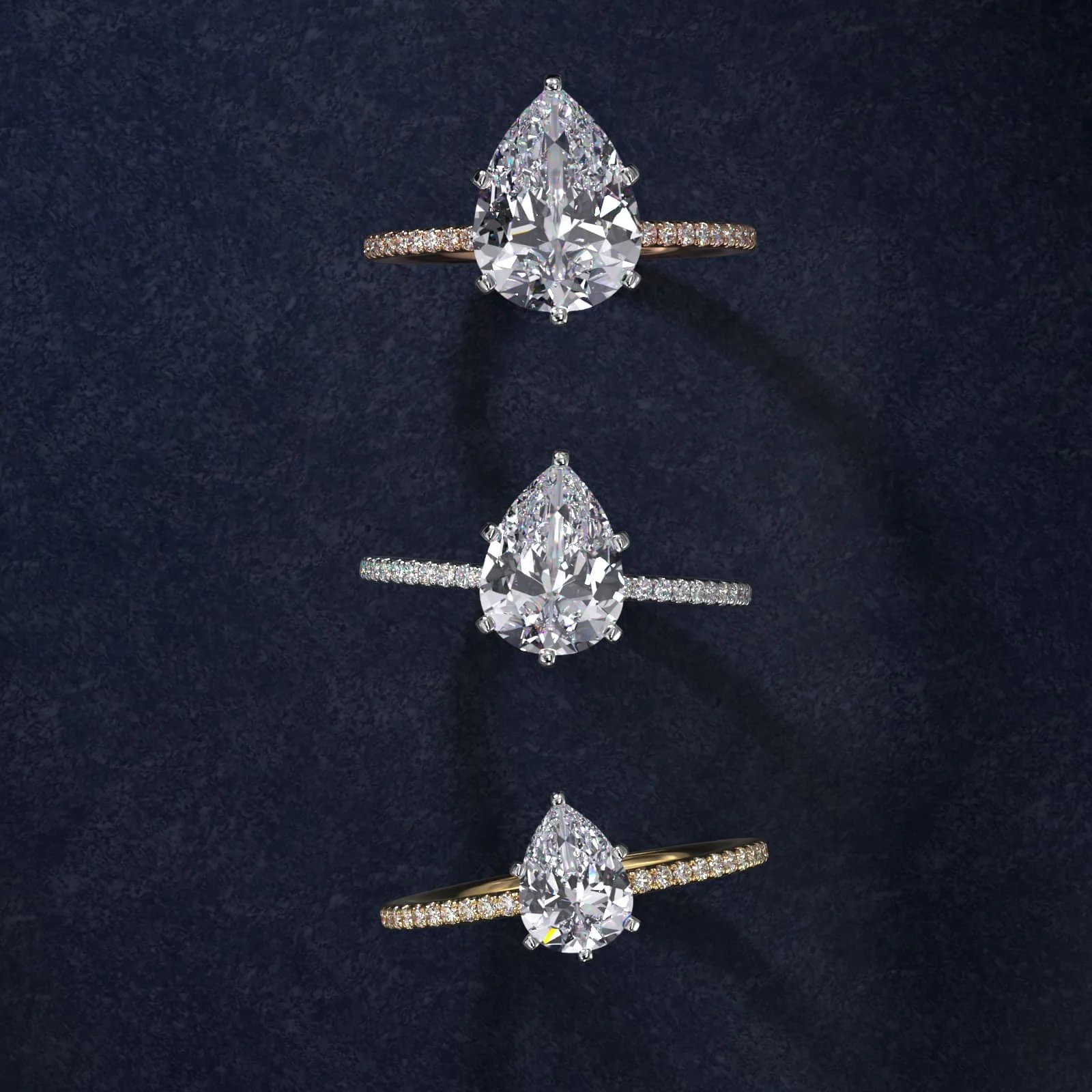 Three diamond rings with pear-shaped center stones displayed on a dark surface.