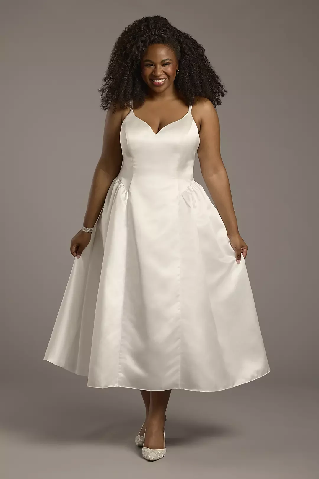 Woman in a white satin wedding dress smiling at the camera