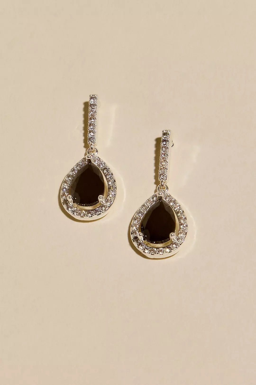 Pair of teardrop-shaped earrings with black stones and surrounded by small white stones.