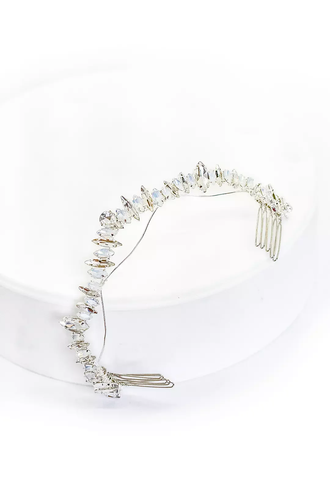 A silver tiara adorned with clear, faceted crystals arranged in a zigzag pattern, displayed on a white surface.