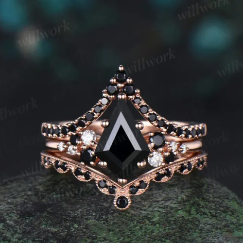 Rose gold ring with black and white gemstones and a black triangular gemstone at the center