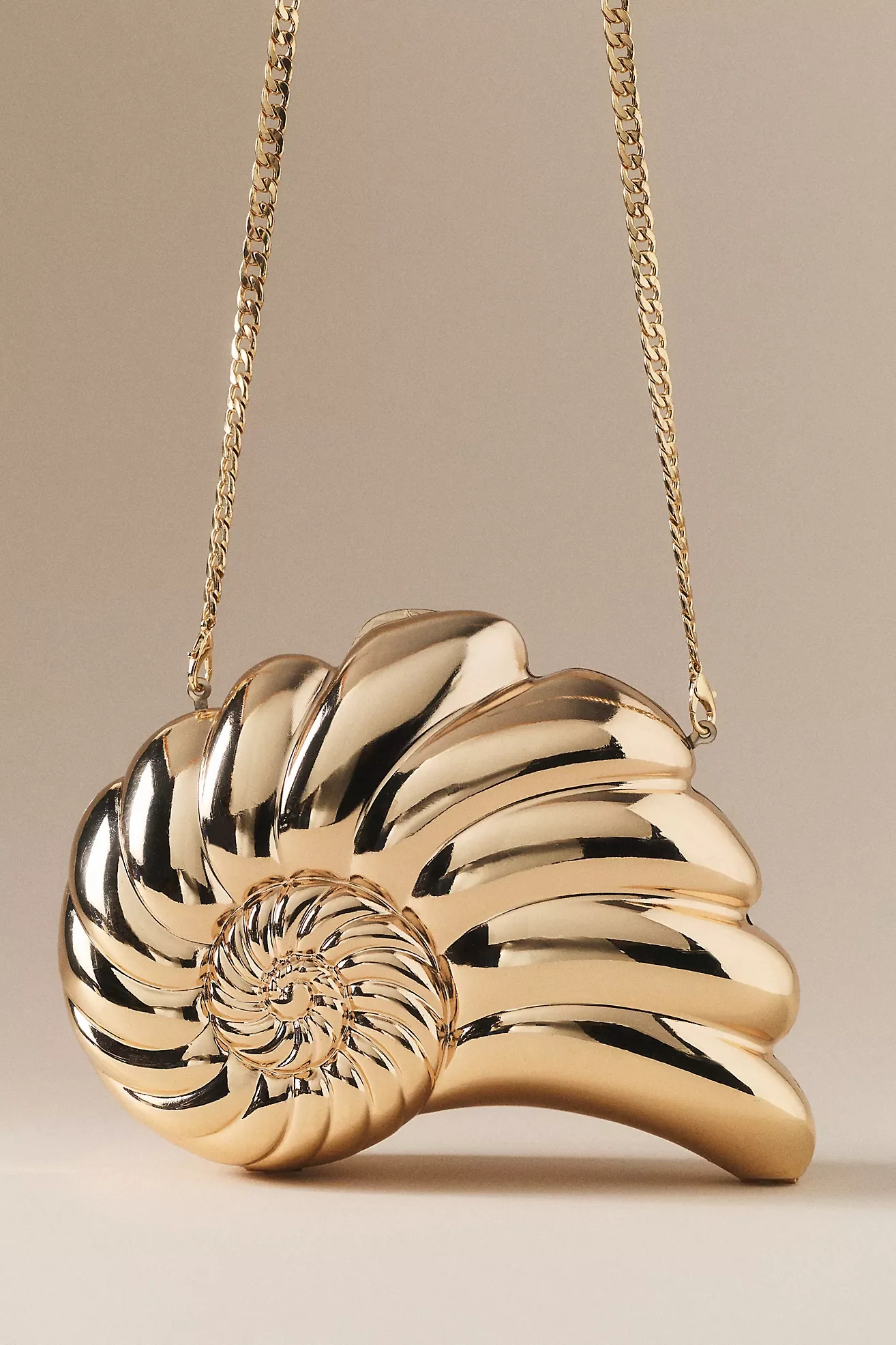 A shiny, metallic spiral shell-shaped handbag with a matching chain strap.