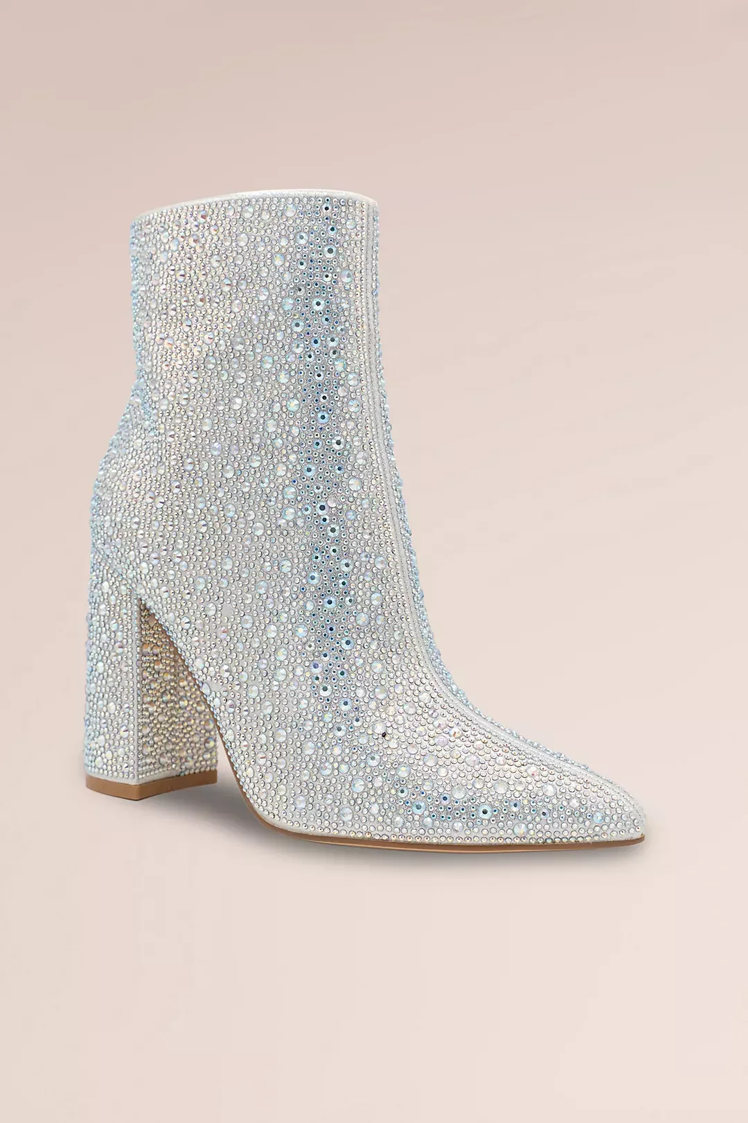 A high-heeled shoe covered in numerous small, round, sparkling stones, with a pointed toe and a thick heel, set against a pale pink background.