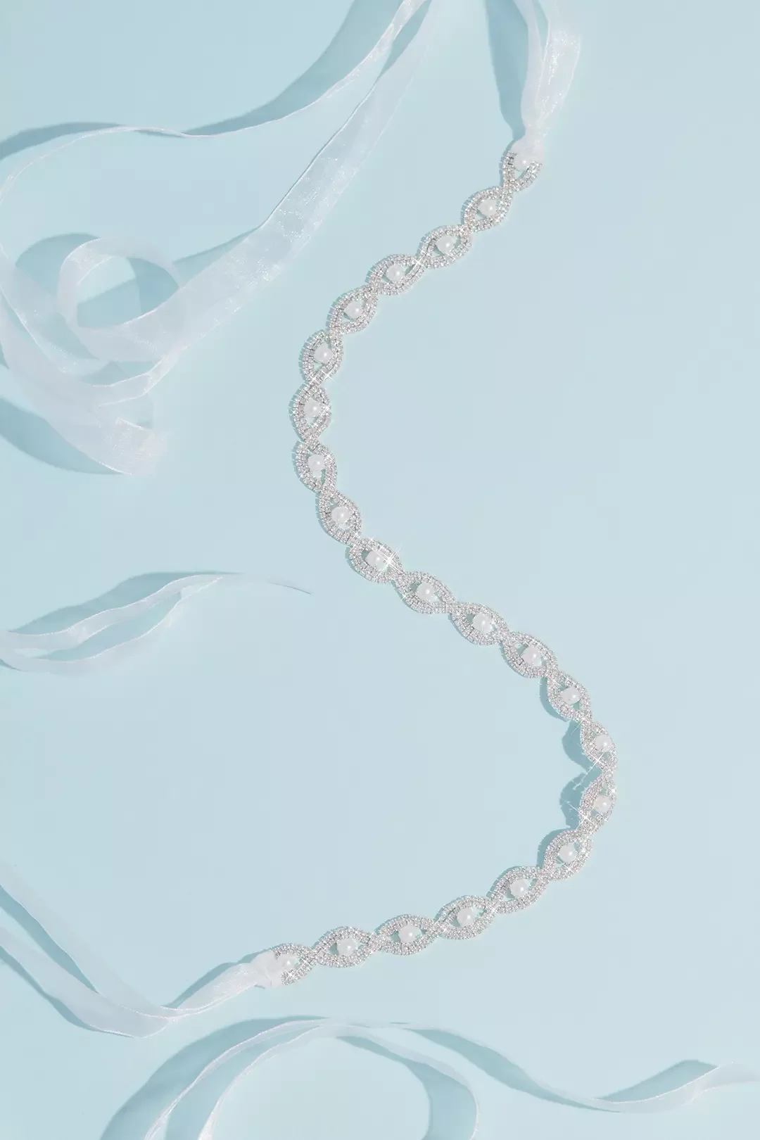 Silver necklace with an interlinked circular pattern placed on a light blue background, accompanied by white ribbons.