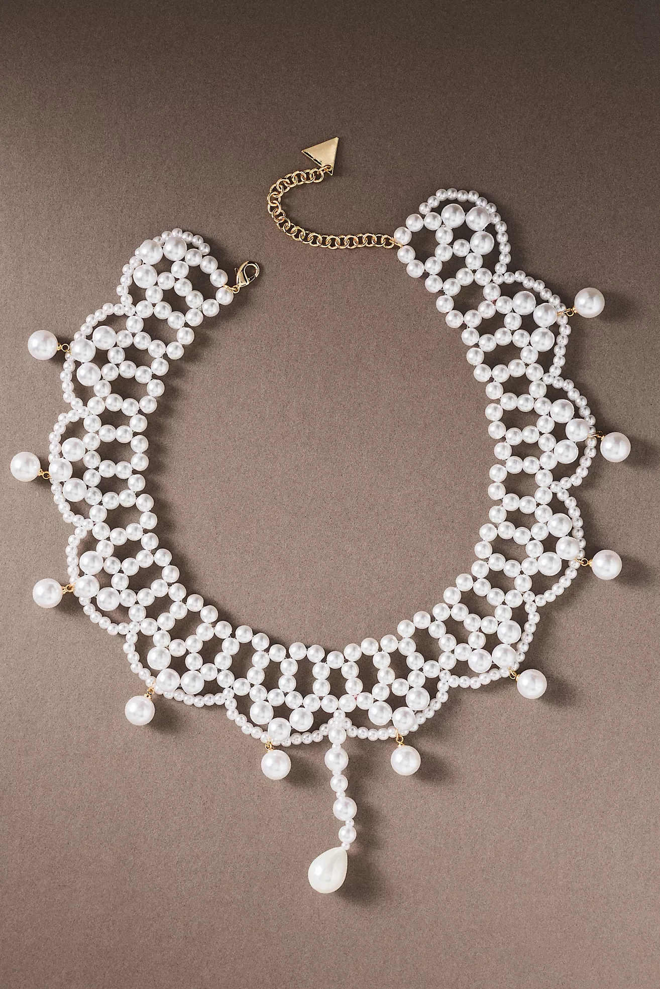 Multiple layered pearl necklaces with large pearl pendants on a neutral background.
