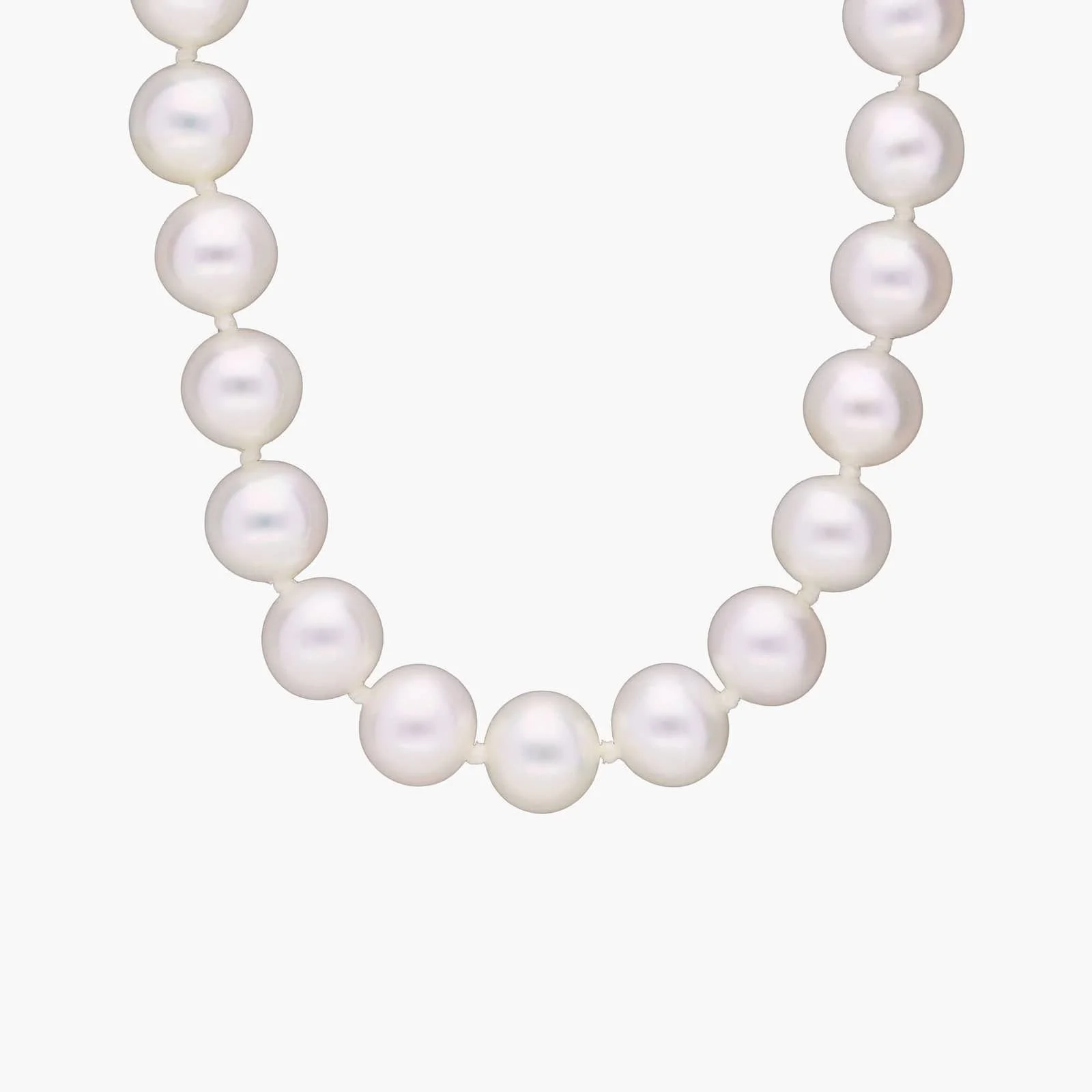Close-up of a pearl necklace with white pearls on a light background.