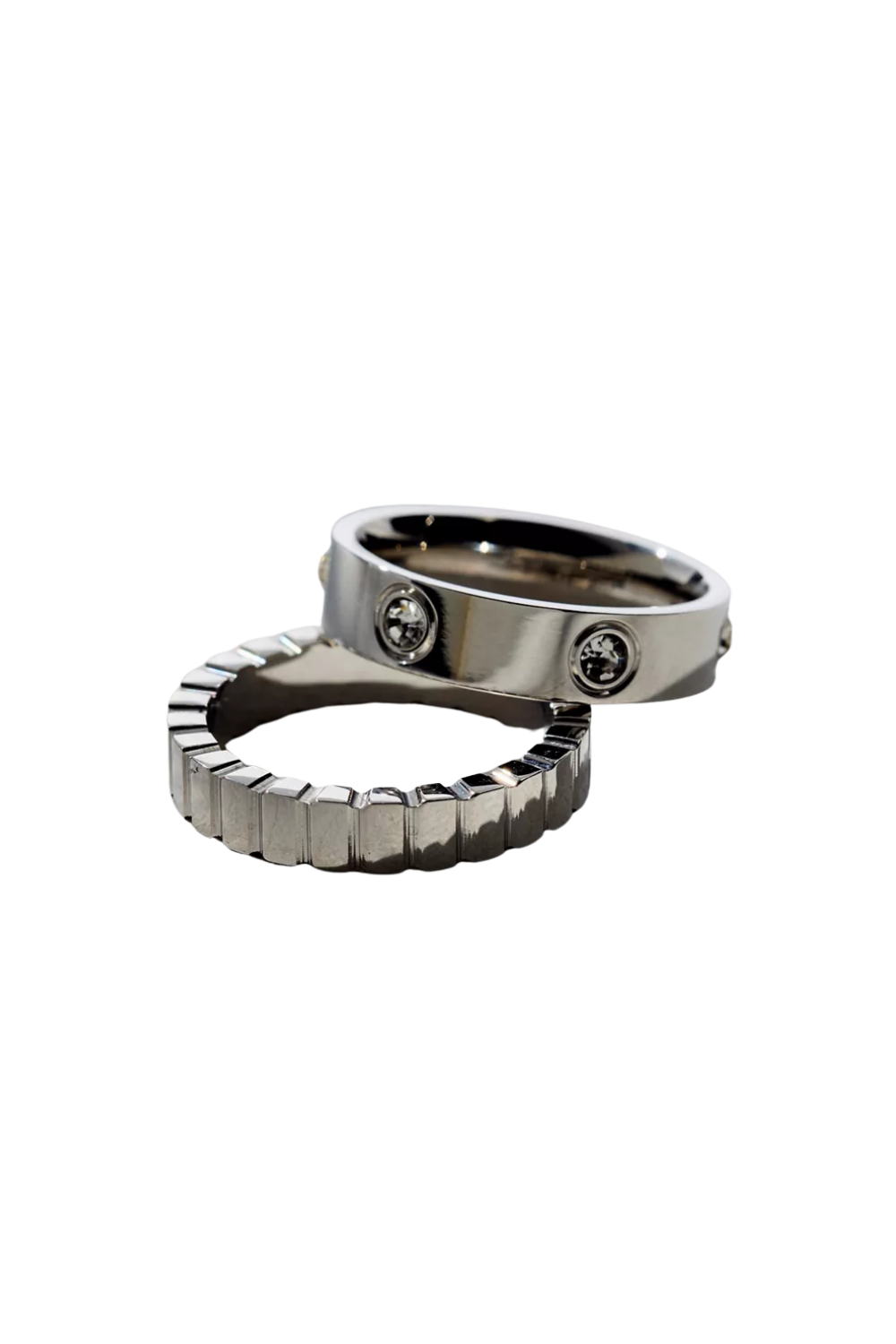 Close-up of two silver rings, one with embedded diamonds, positioned on a black background.