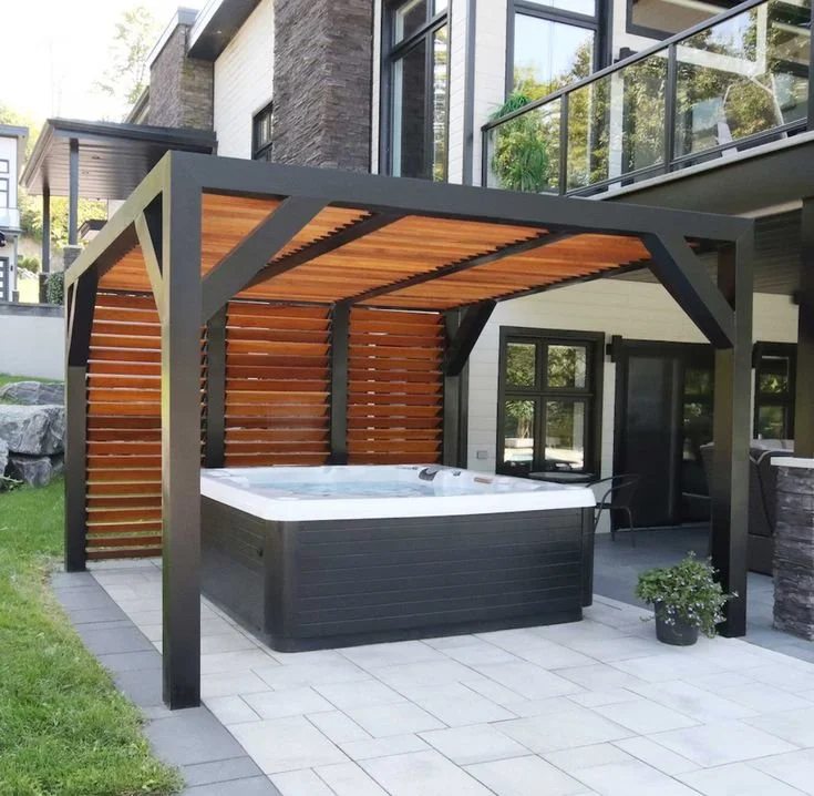 Outdoor hot tub with a wooden privacy screen and a pergola cover on a patio.