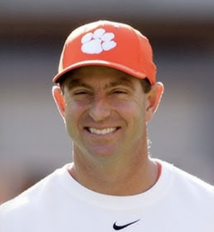 A smiling man wearing a red baseball cap with a white paw print logo and a white Nike t-shirt.