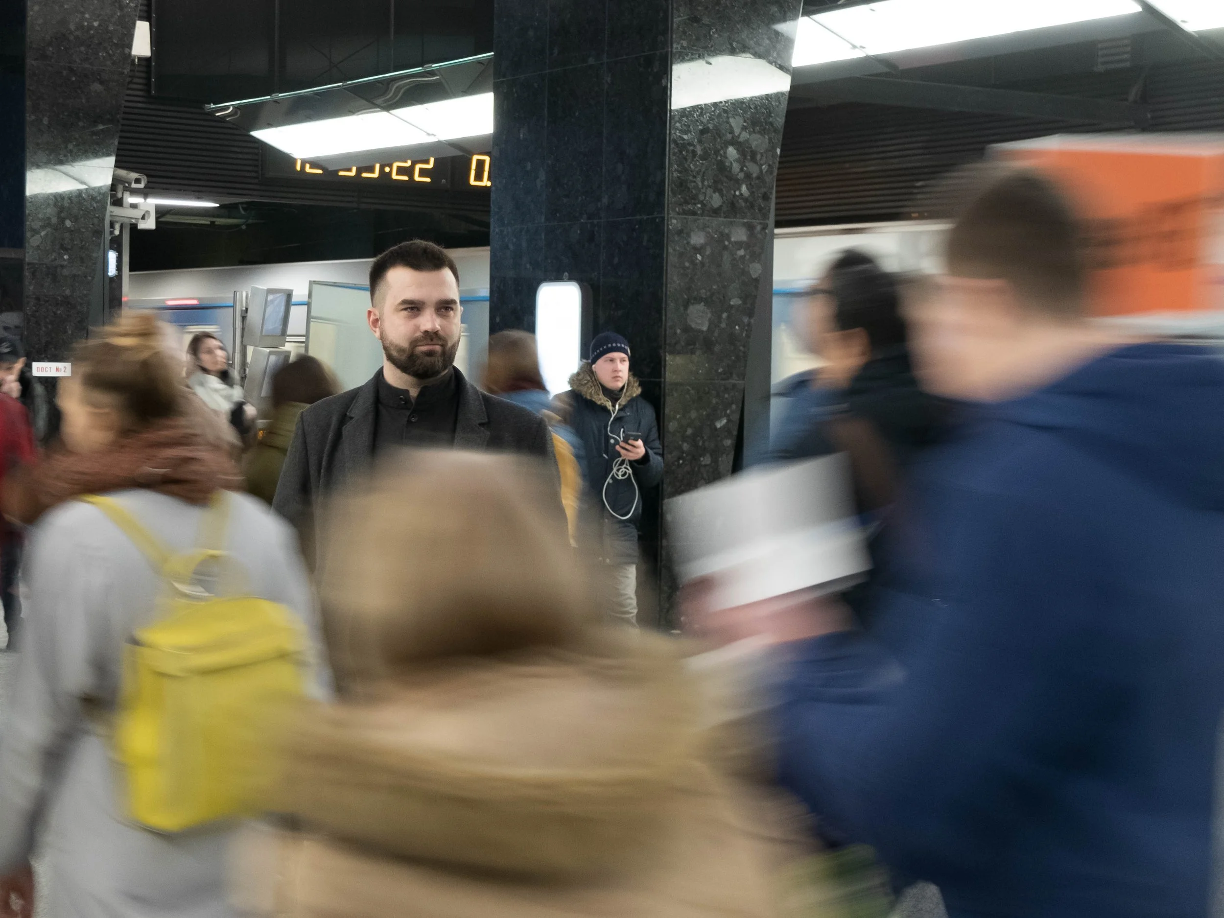 A man paused in focus, suggesting comtemplation, against a blurred crowd