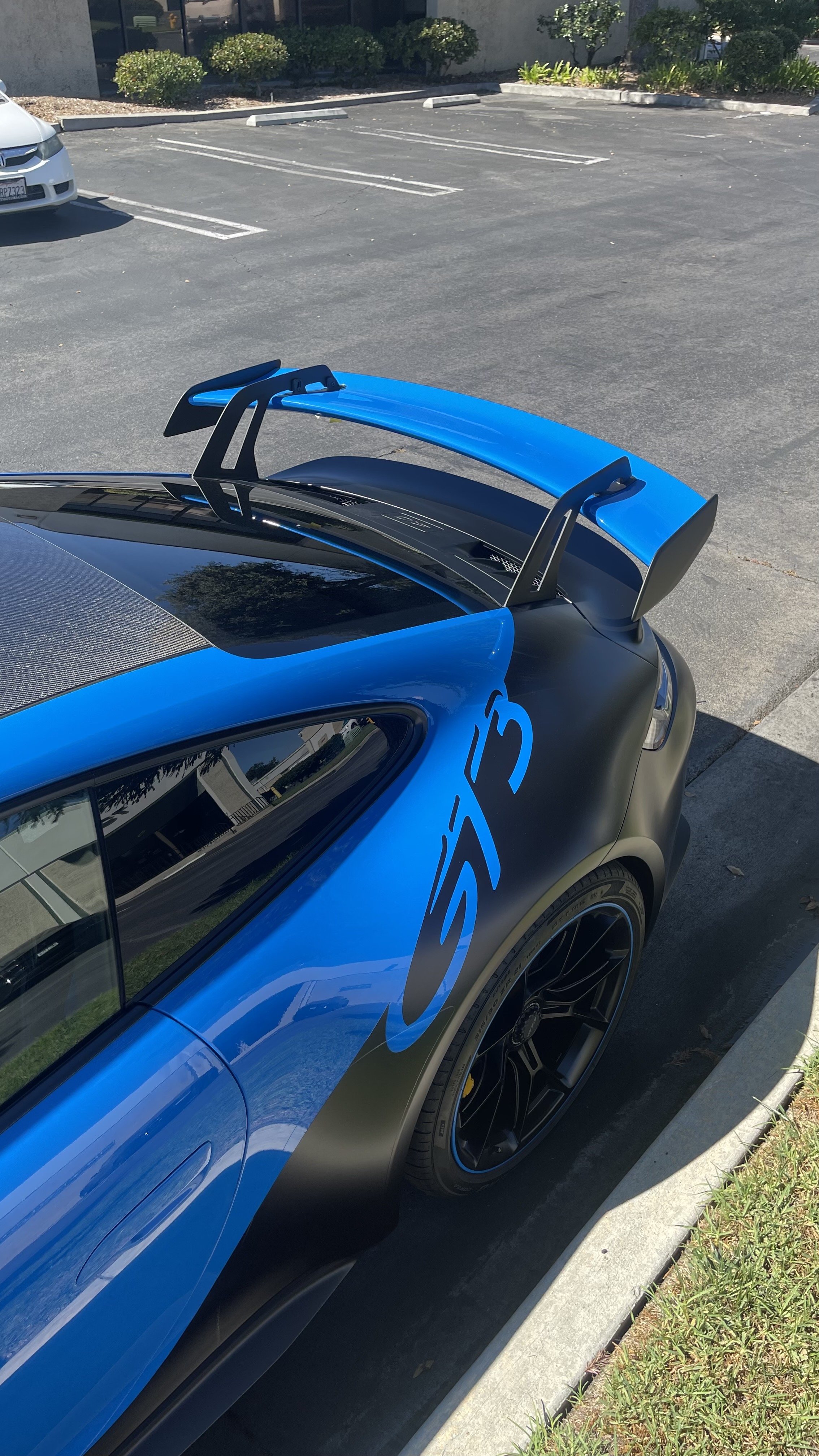 A close-up view of a blue and black Porsche gt3 wrapped with custom satin black lettering vinyl wrap