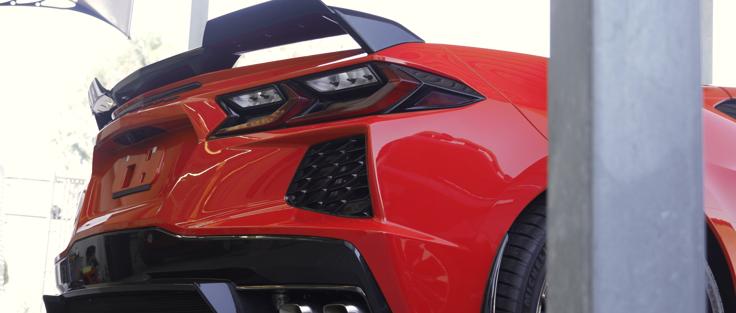 Red sports car parked in a garage, showing the rear and side, with black spoiler and modern taillights. C8 Corvette stingray 70th anniversary  edition full body clear paint protection fit ( PPF ).
