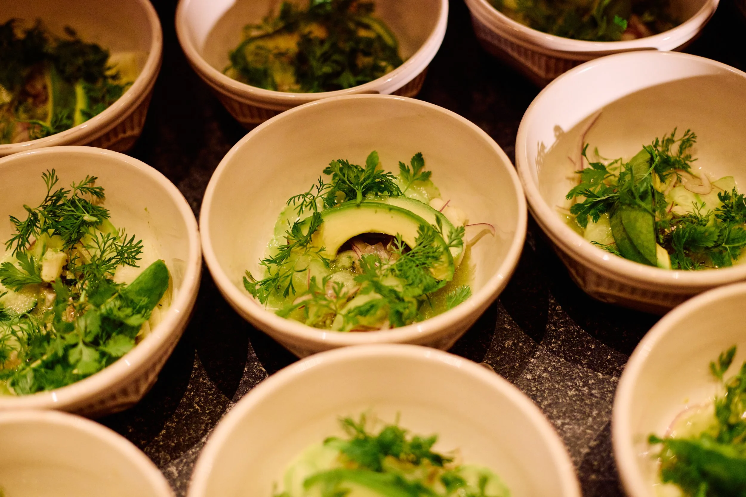 Small bowls of fresh salad with spinach, cucumber, and herbs garnished with parsley and other greens