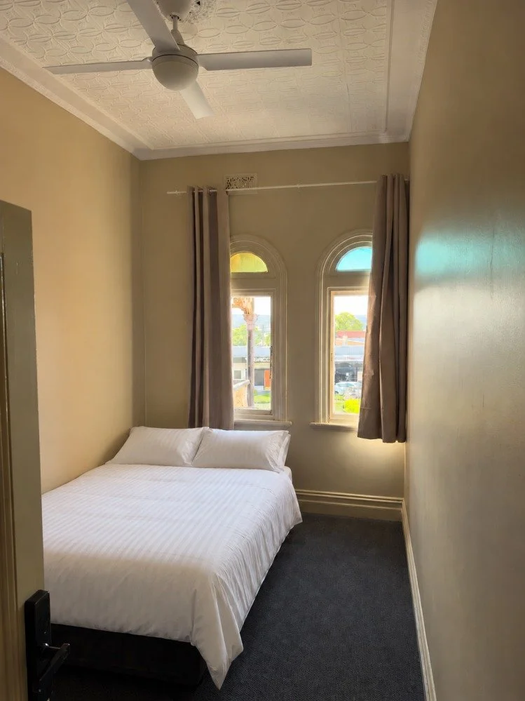 Double room with a ceiling fan and arched windows at Kookaburra Rooms, Kurri Kurri Hotel