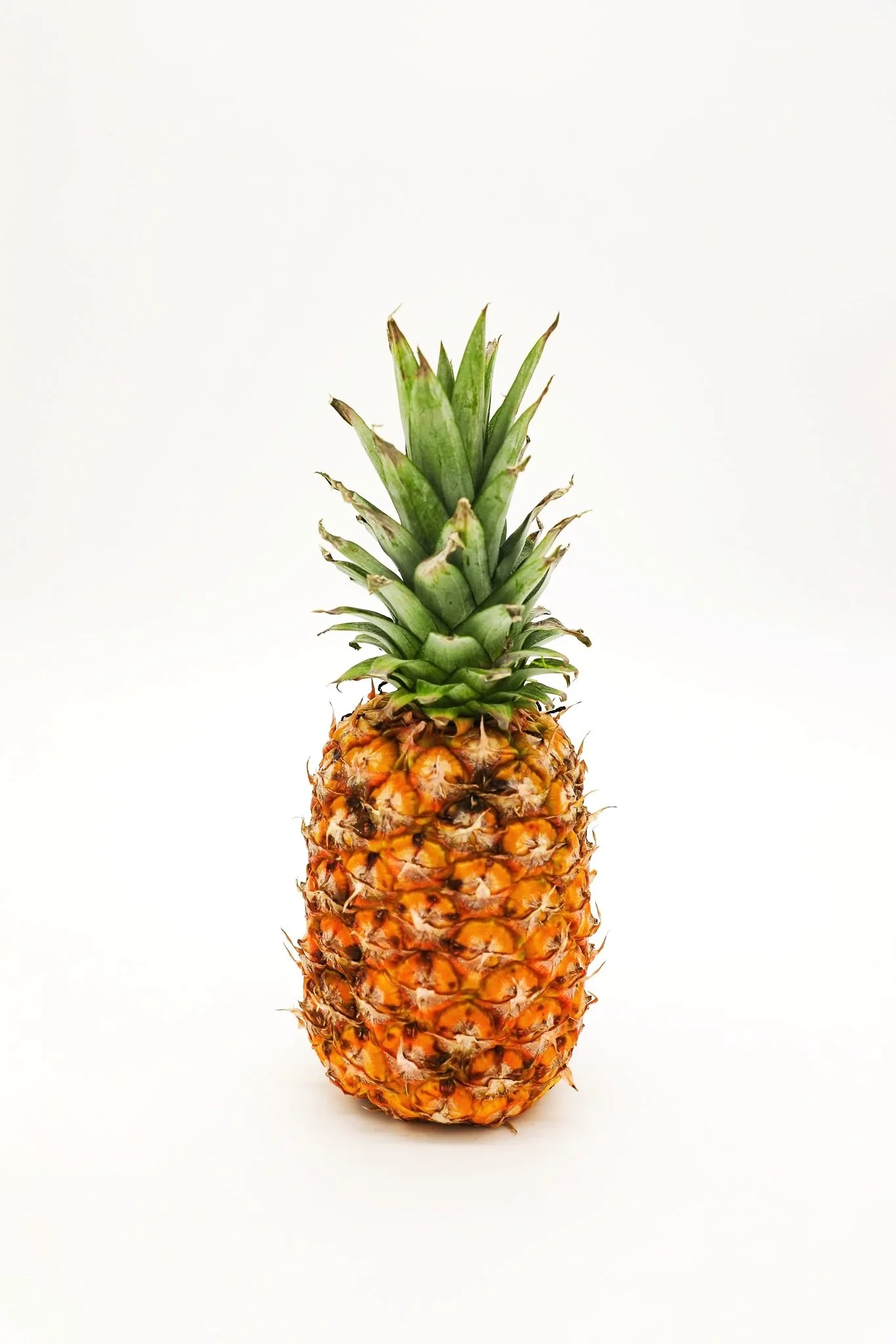 Fresh pineapple with green spiky crown on a white background.