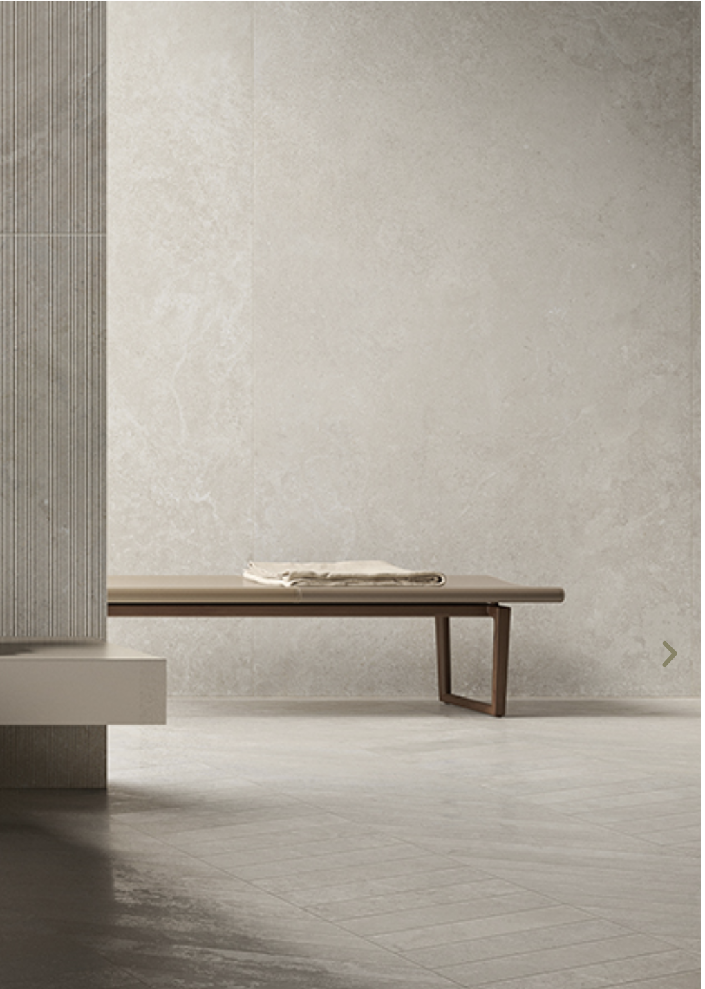 Minimalist interior space with a wooden bench and a folded cloth on top, neutral-colored walls, and a textured vertical panel on the left side.