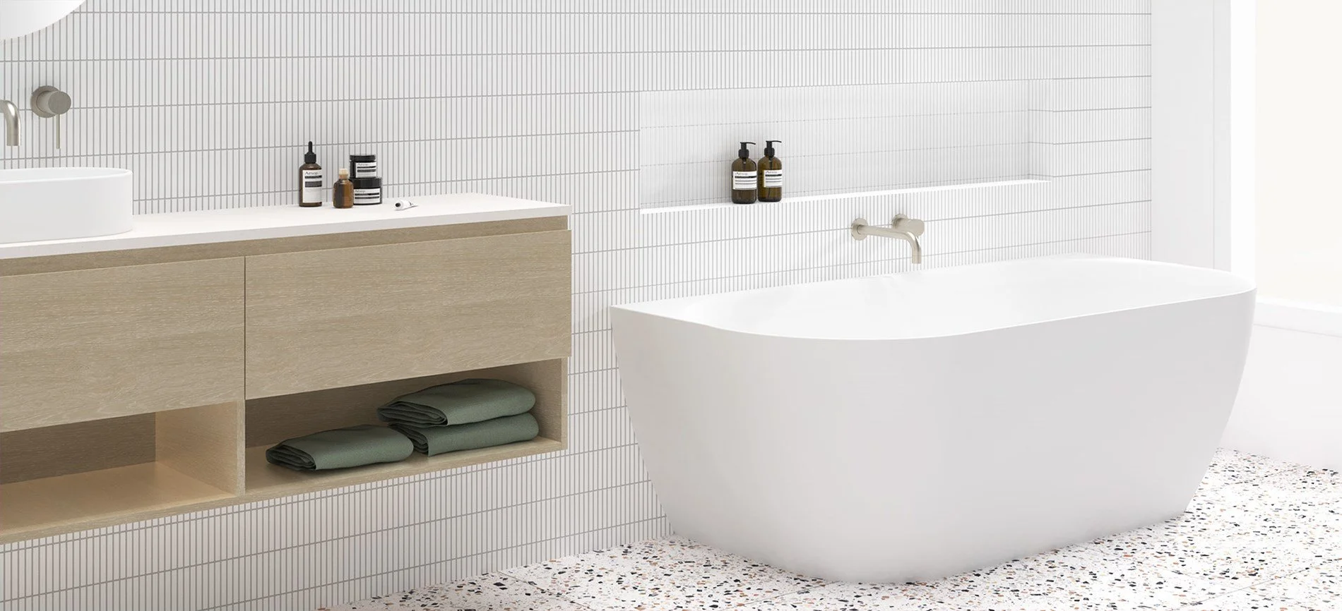Modern bathroom with a built-in vanity with storage, a white freestanding bathtub, and a tiled wall with bathroom products.