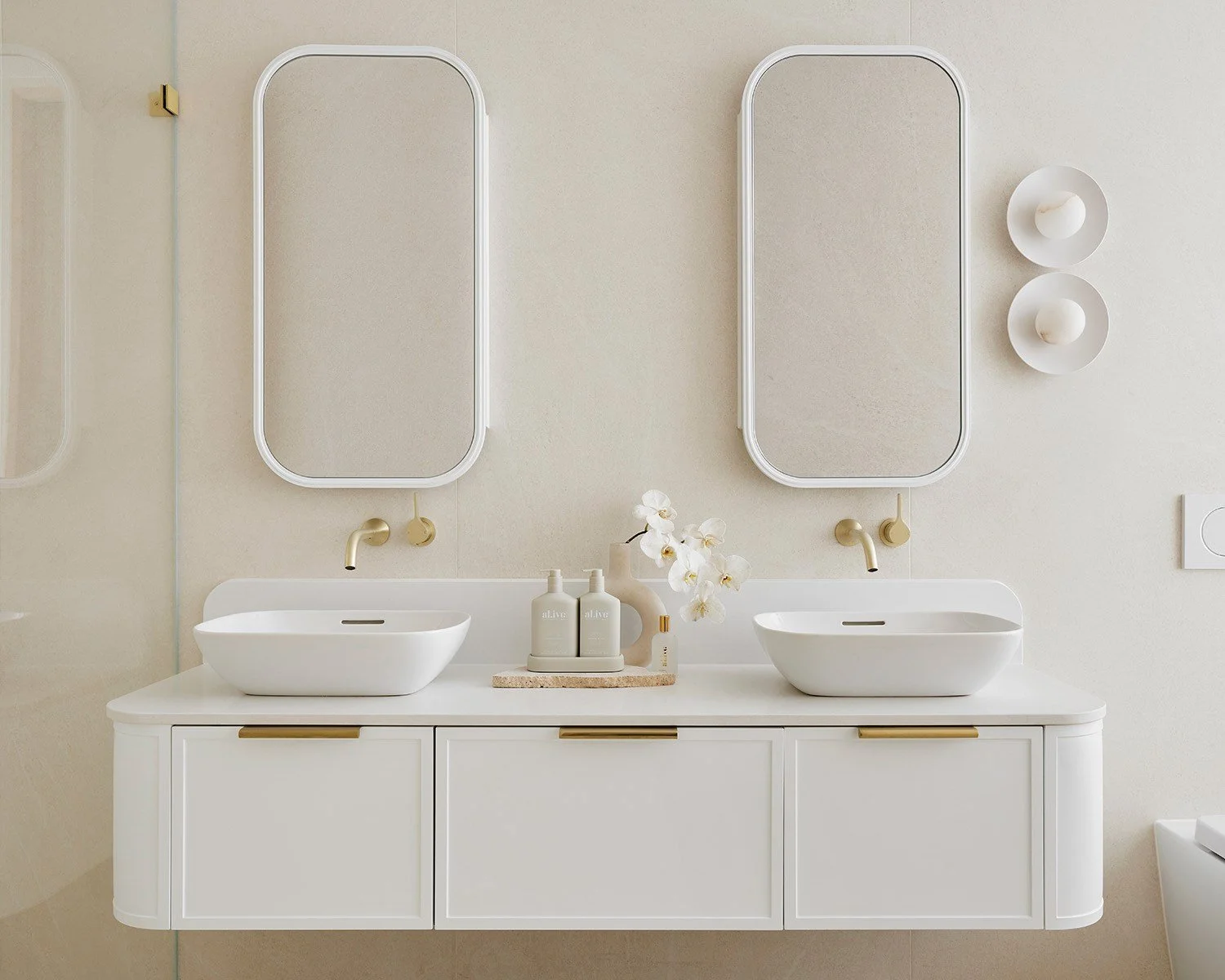 A modern, minimalist bathroom vanity with two vessel sinks, two mirrors, and neutral decor.