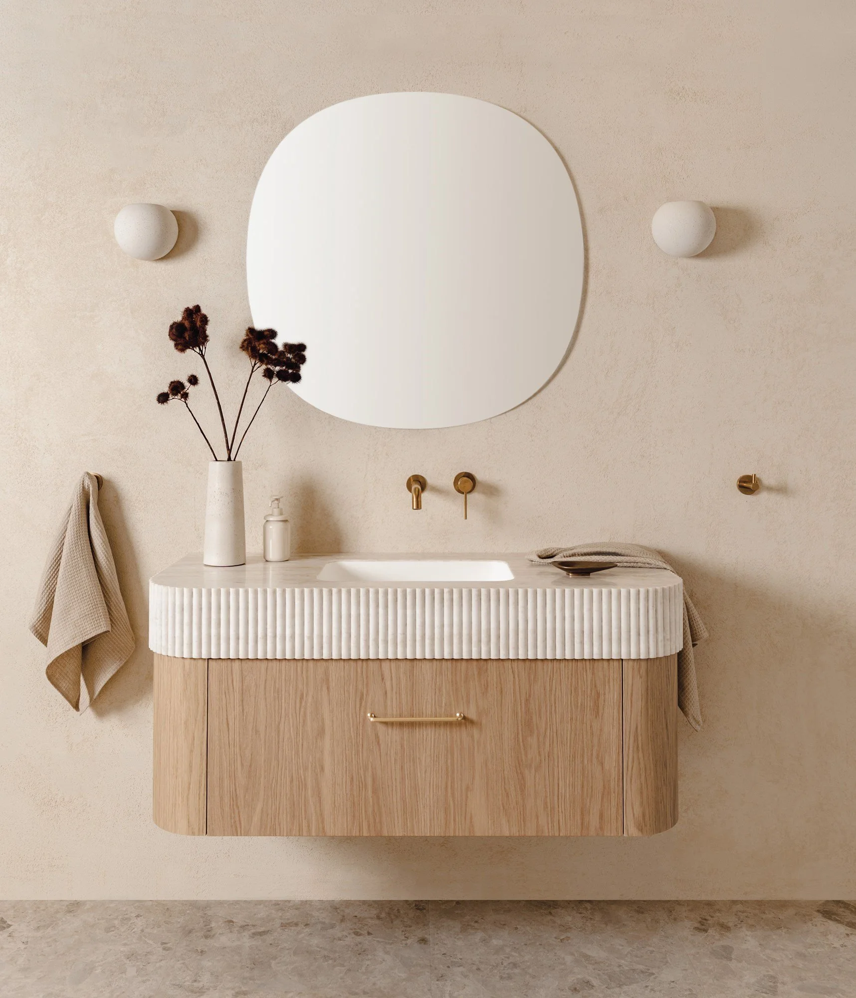 Modern bathroom vanity with a round mirror, a vase with dried flowers, a soap dispenser, and folded towels, mounted on a beige wall.