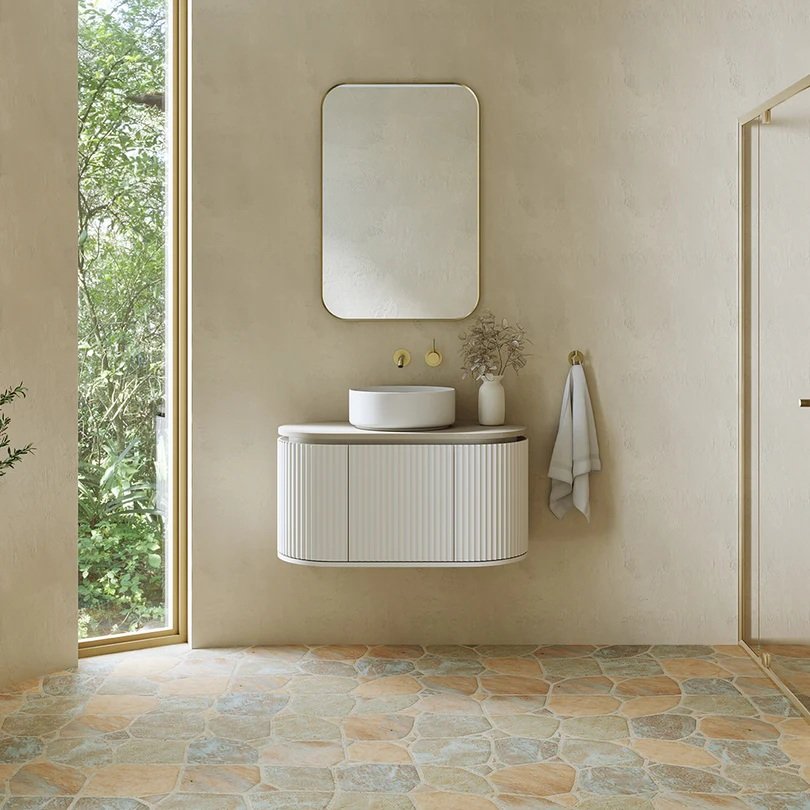 Modern bathroom with a floating vanity, vessel sink, round mirror, and beige tiled floor.