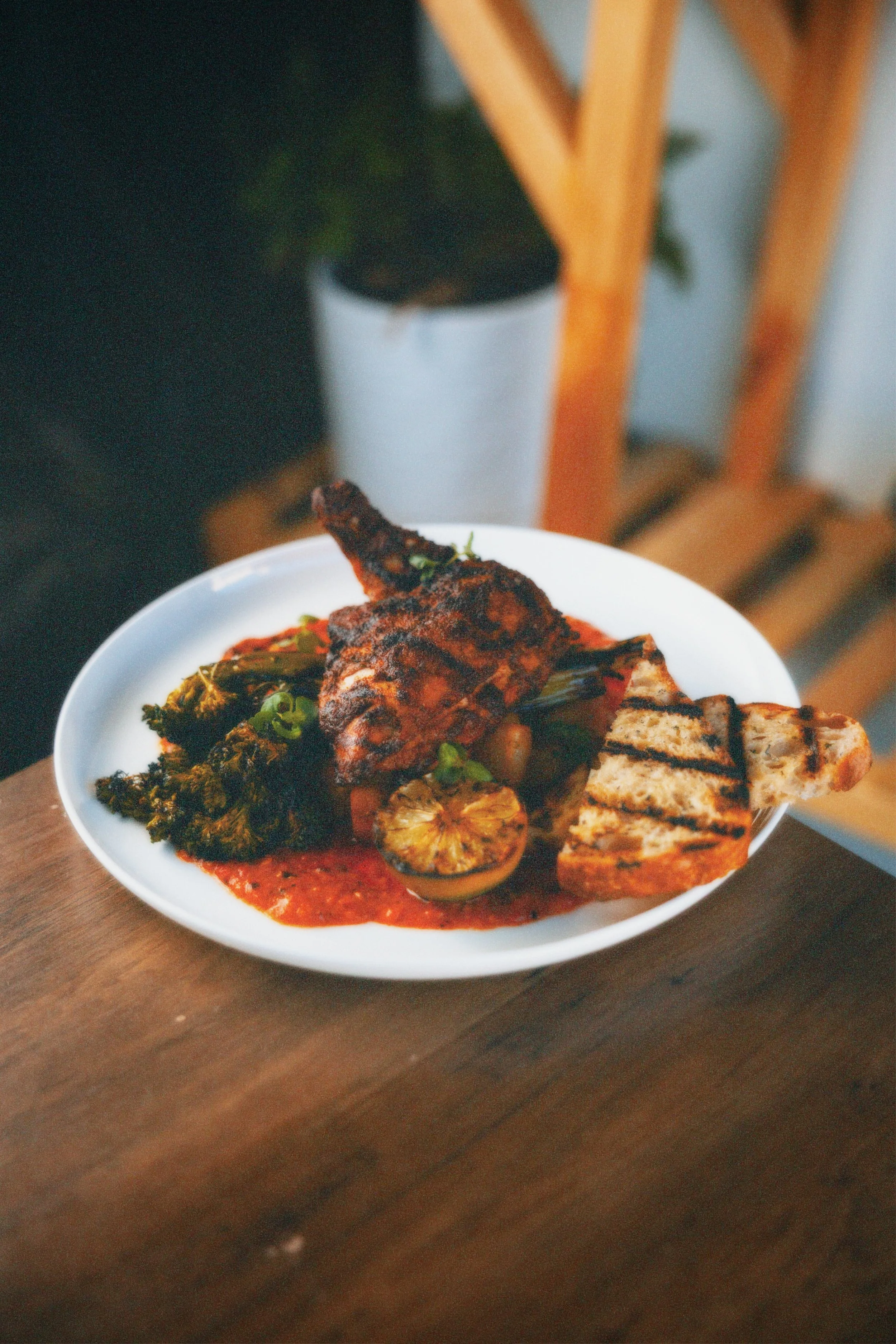 Plate of grilled chicken, grilled vegetables, and rice with sauce.