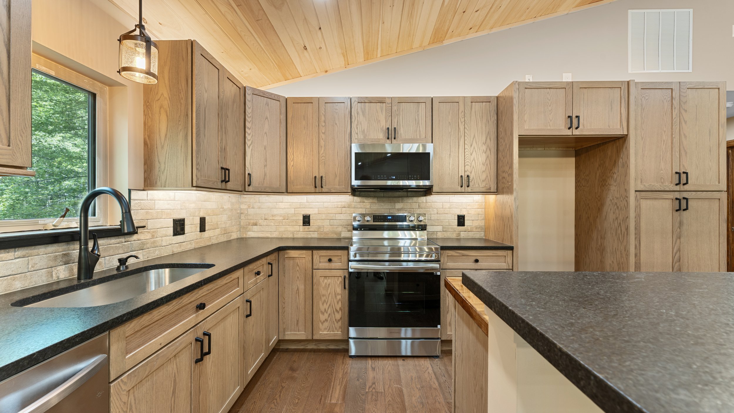 Backyard view of a two-story house with a covered porch, stairs, and a garden with bushes and trees, during dusk.