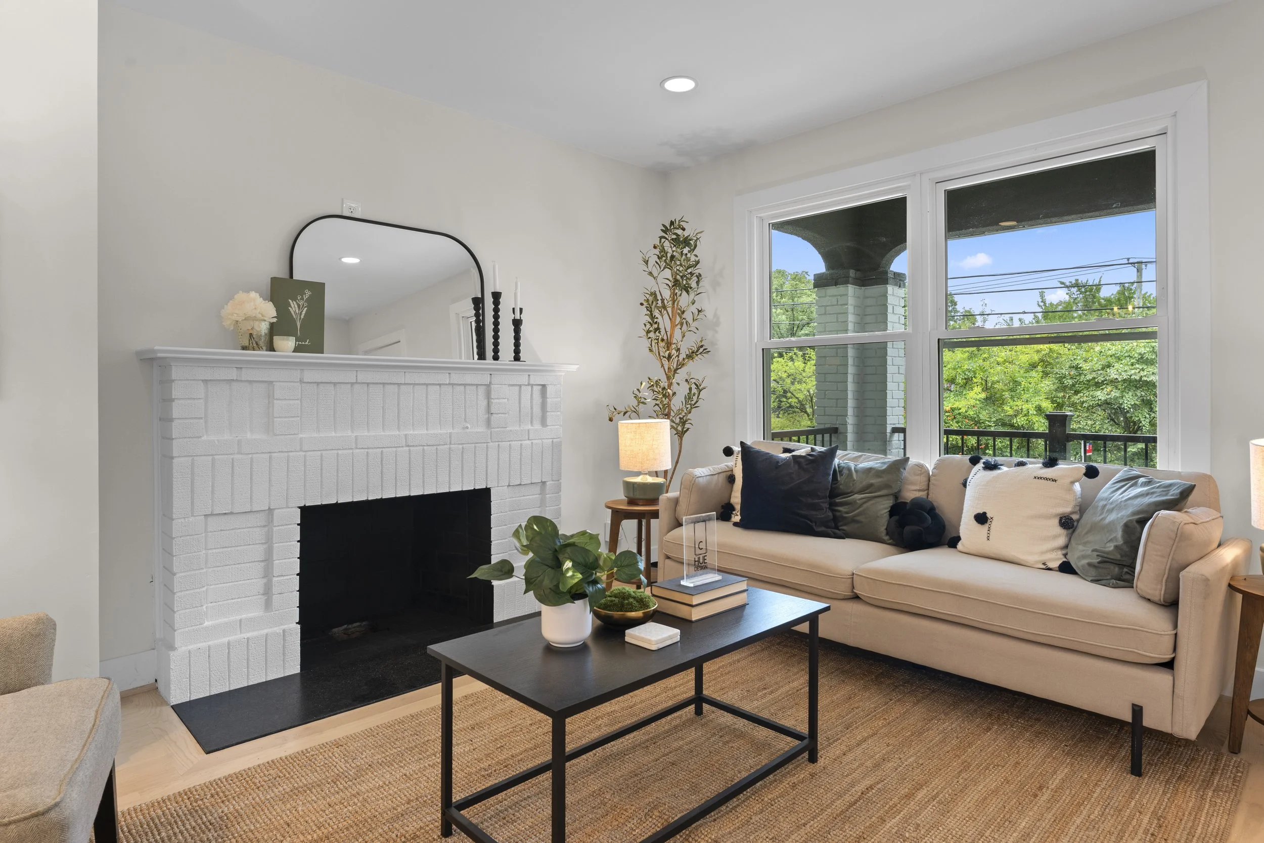 Front yard and driveway of a suburban house with trees, shrubs, a mailbox, and a garage under a partly cloudy blue sky.