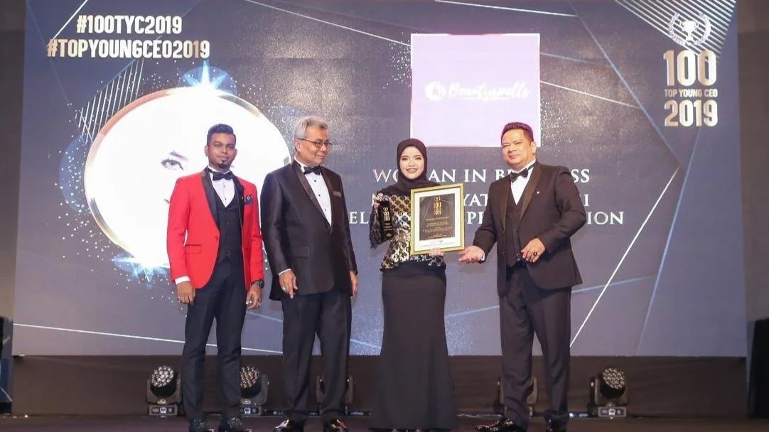 Group of four people in formal attire on stage, holding an award plaque at the 100 Top Young CEO 2019 event.