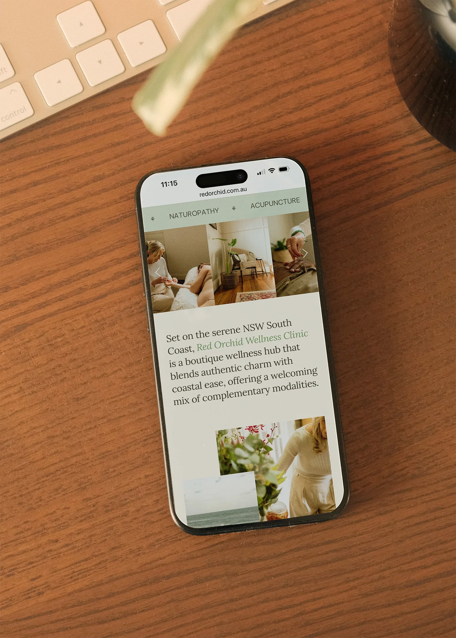 A smartphone on a wooden desk displaying a website for Red Orchid Wellness Clinic, with tabs labeled NATUROPATHY and ACUPUNCTURE, and images of a therapy session, a plant, and a person in a wellness setting.
