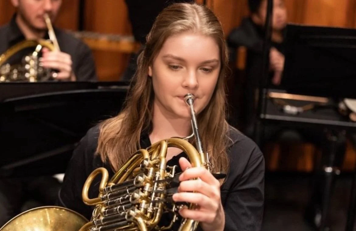 A woman playing a French horn during a musical performance.