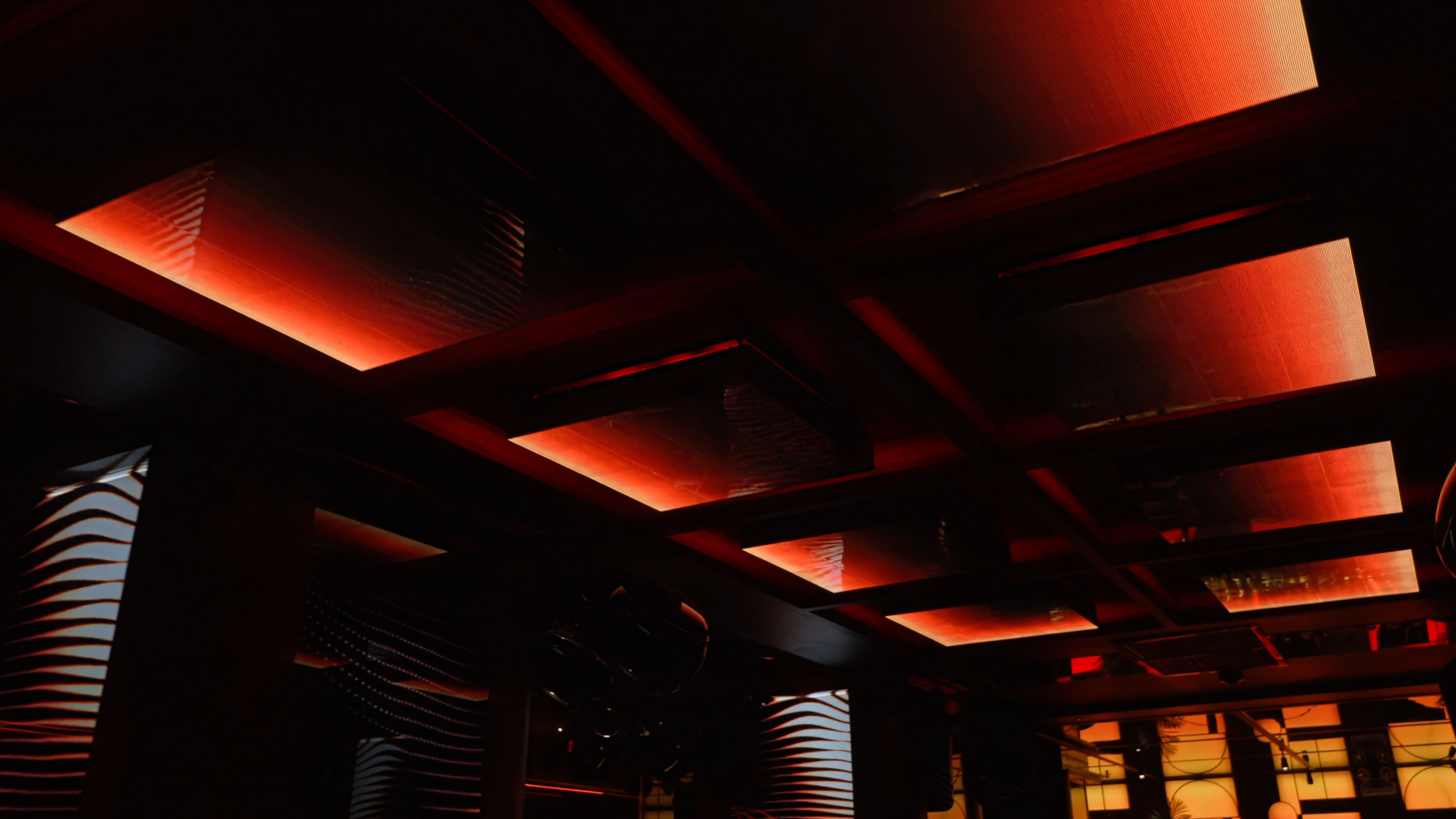 Interior ceiling with modern rectangular red and orange LED panels and black structural elements.