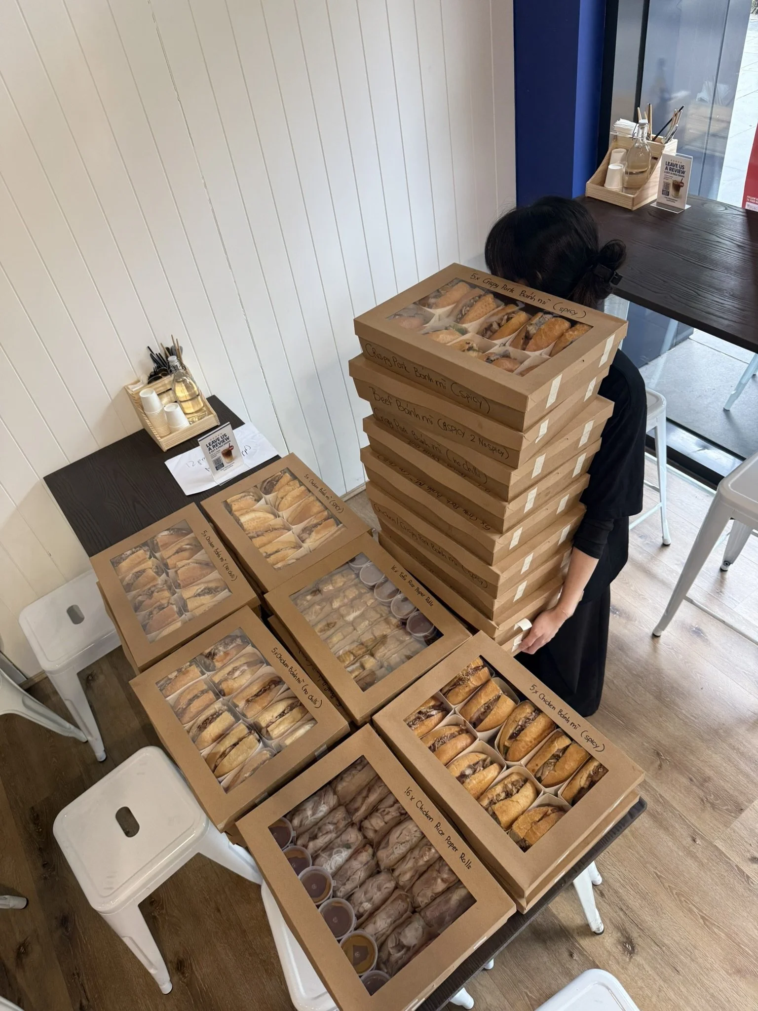 a boxed collection of LA'SEN’s catered food options, including a range of banh mi and rice paper rolls.