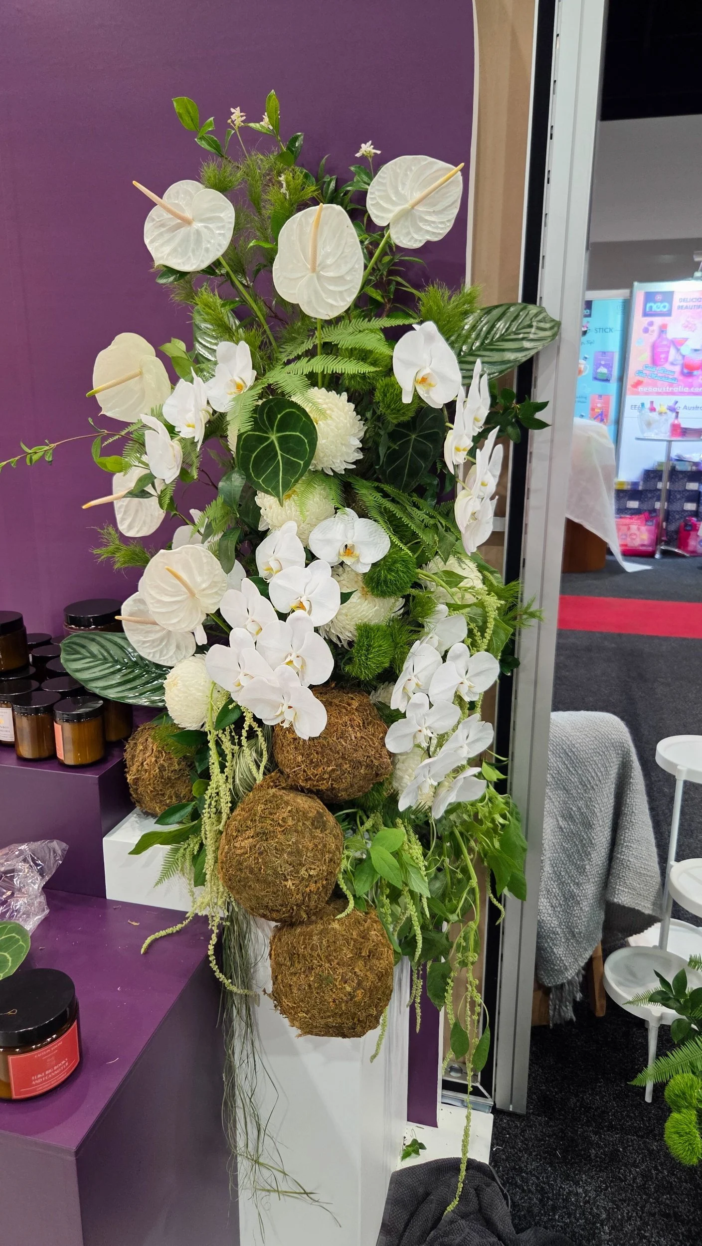 tall installation with orchids, anthuriums trpoical leaves