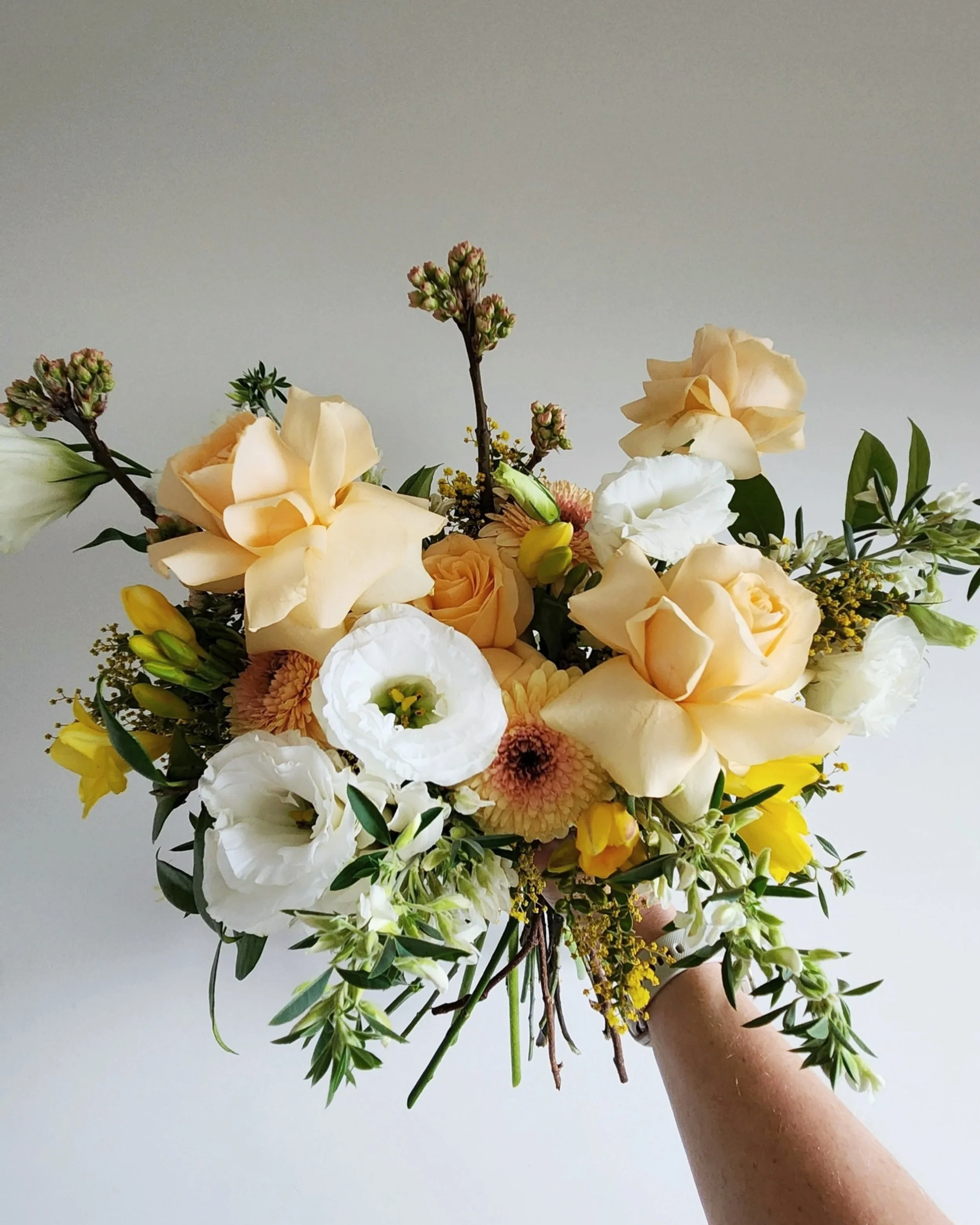 wedding bouquet in peaches, yellow and whites. roses, lisianthus and freesias with seasonal textures 