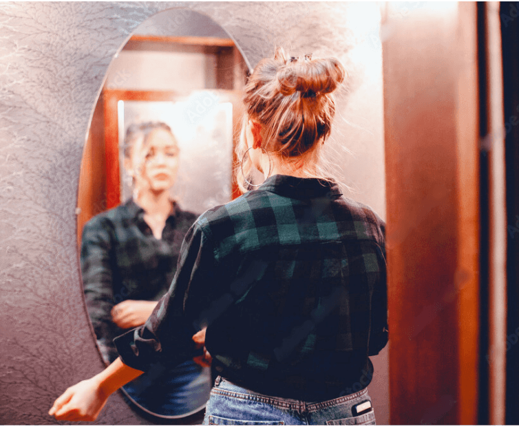 empowering photo of a mom looking in the mirror rolling up sleeves