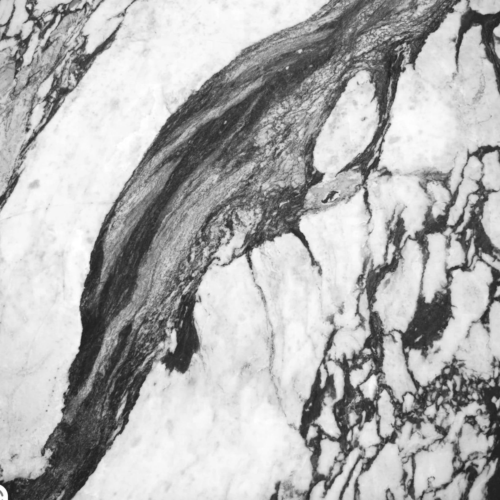 En pedestal med marmormønster på overfladen, placeret på en hvid flade med grå baggrund. Kube piedestal i den smukke high-end marmor Calacatta Viola.