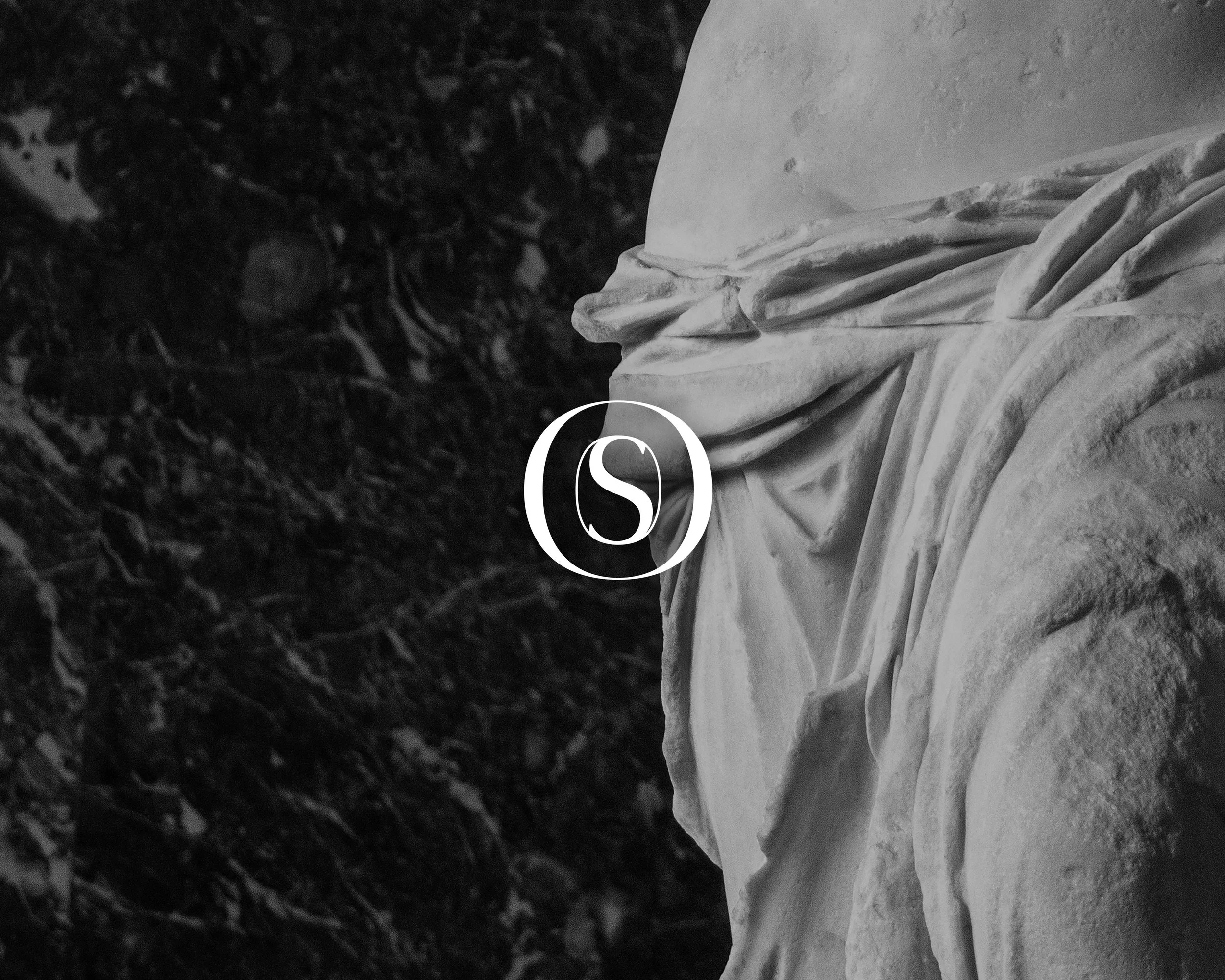 Nærbillede af den foldede struktur i en hvid marmorskulptur, med mørk baggrund. Marmor.