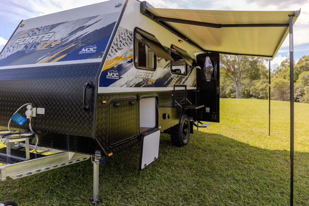 Travel trailer with an extended awning set up on grass.