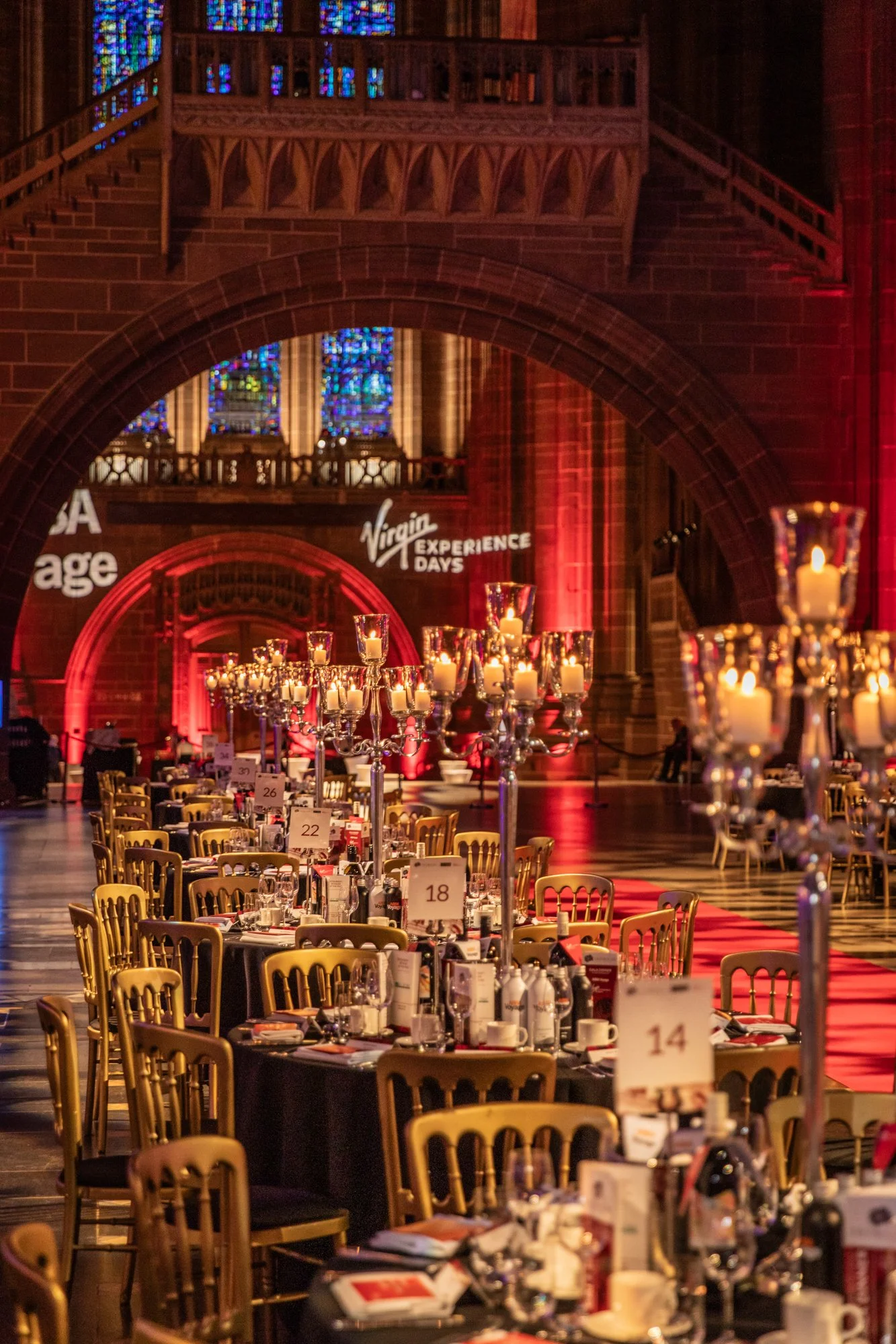 Elegant banquet hall with decorated tables, tall candelabras, and stained glass windows, set for a formal event at Virgin Experience Days.