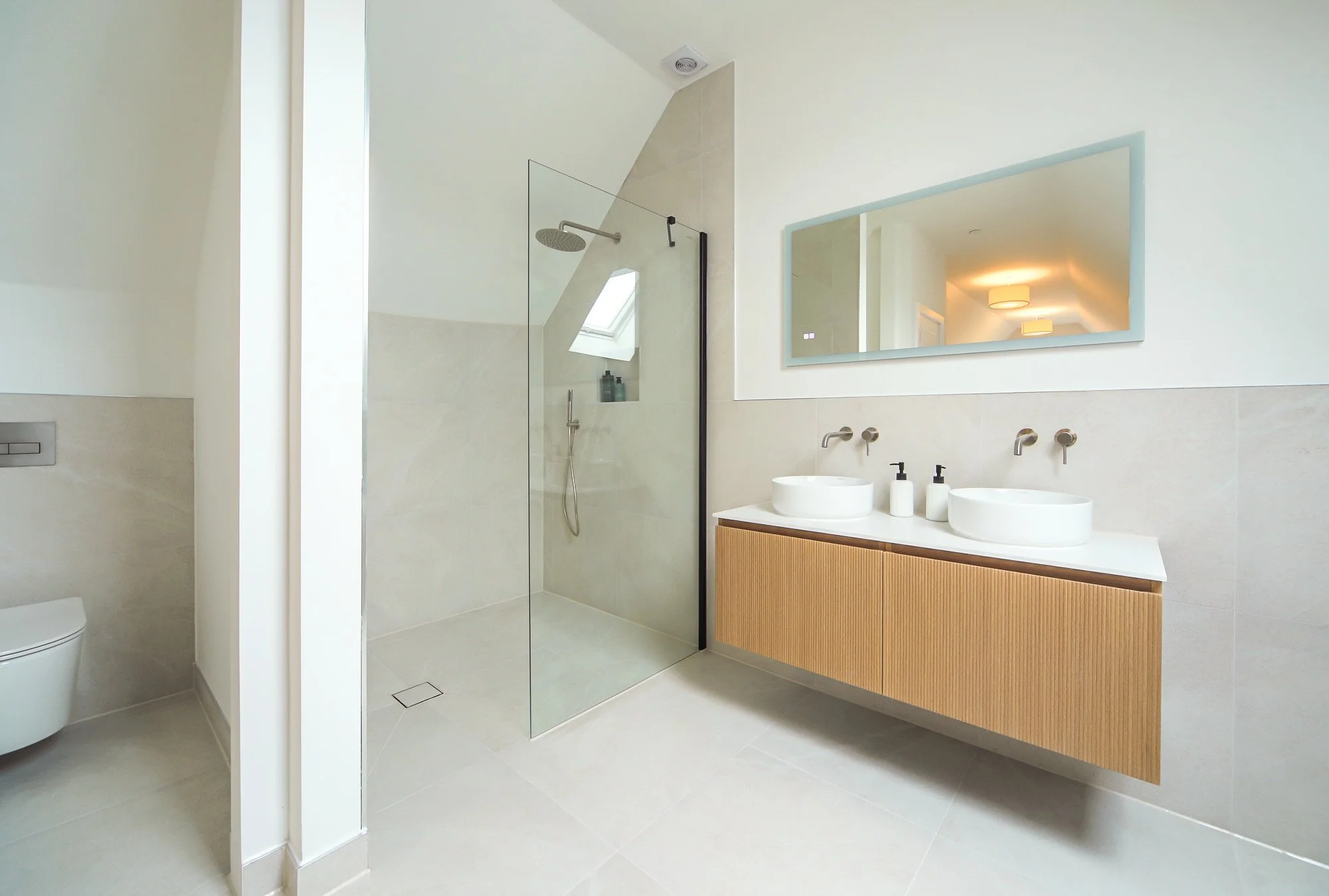 Spacious shower room and basins in a light bathroom in Kent