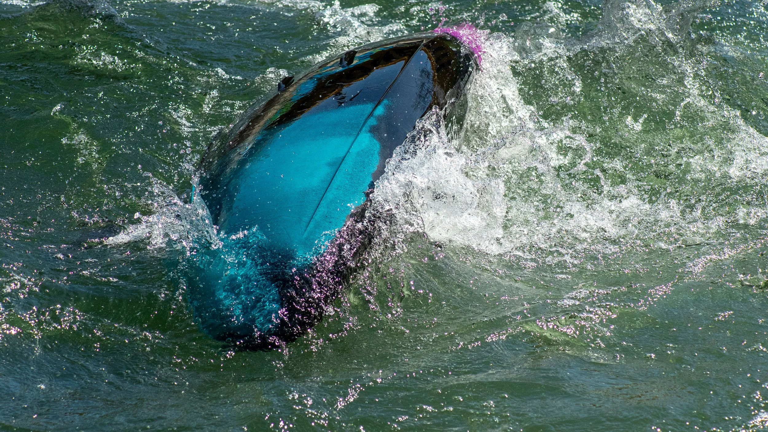 A kayak is capsizing in choppy water.