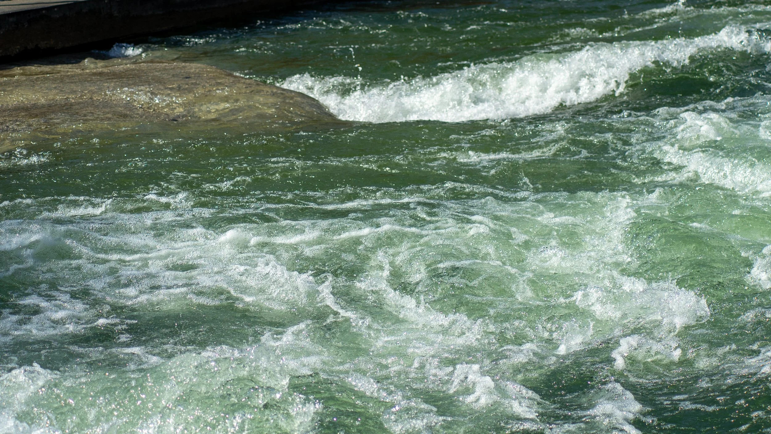 Rough ocean water with waves crashing against rocks.