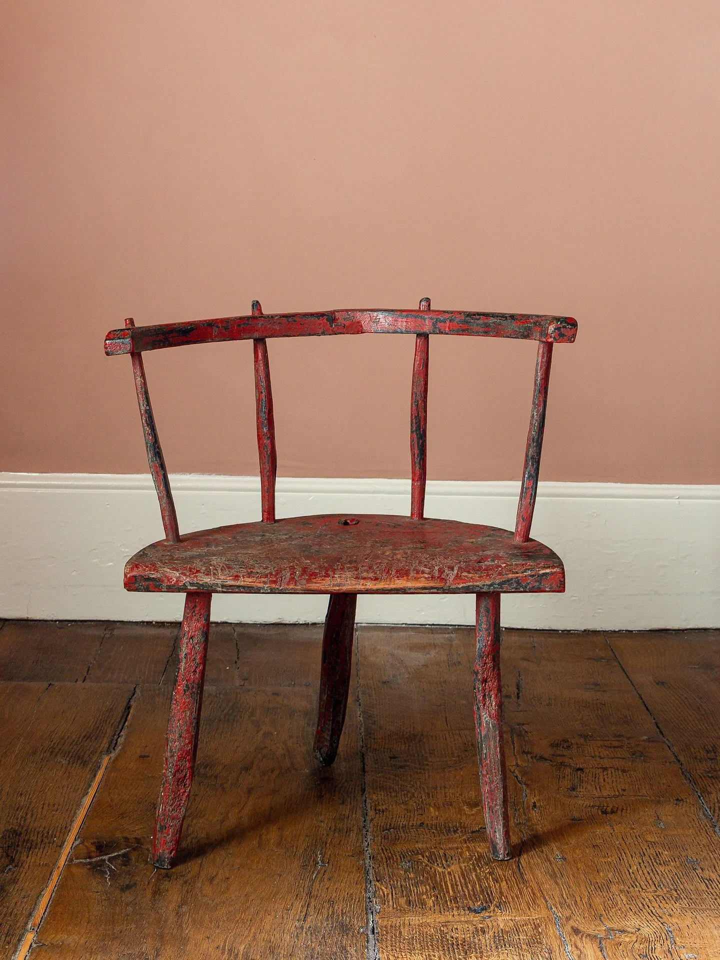 A rare 18th Century childs Welsh stick chair, marked by centuries of use giving it a deeply worn and charming appearance. Retaining much of its original red paint, this primitive chair stands on three gently out-swept legs. An evocative and well-love